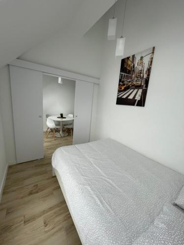 a white bedroom with a bed and a table at Biały Klif in Mechelinki