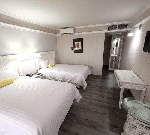a hotel room with two beds and a table at Paraíso Express in Torreón