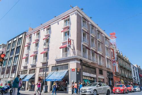 een groot gebouw in een stadsstraat met mensen buiten bij Hotel Posada Guadalupe in Puebla