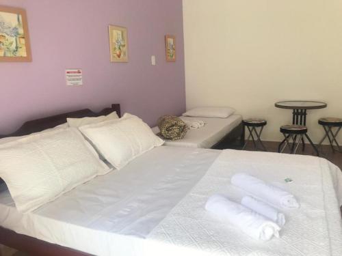 a bedroom with a bed with white sheets and pillows at Pousada Sonho Meu in Itanhandu