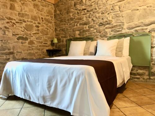 a bed in a room with a stone wall at Cascina Bertolotto Wine Resort in Spigno Monferrato