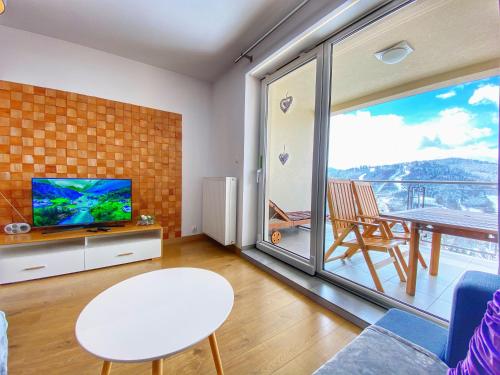 a living room with a tv and a large window at Apartamenty Szóstka Wisła Kamienna in Wisła