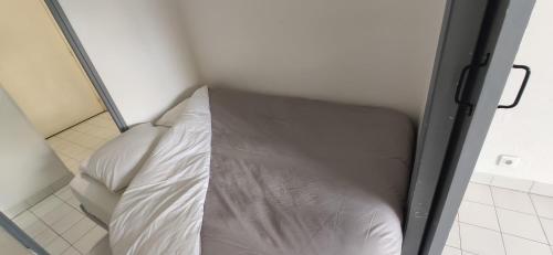 uma cama num pequeno quarto com lençóis brancos em jujuceline83 em Fréjus