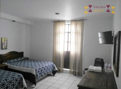 1 dormitorio con 2 camas, mesa y ventana en Hotel Plaza Iberia, en Tehuacán