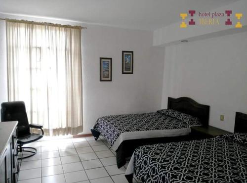 una habitación de hotel con 2 camas y una silla en Hotel Plaza Iberia, en Tehuacán