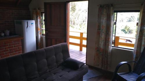 ein Wohnzimmer mit einem Sofa und einem großen Fenster in der Unterkunft Chalé Portal Lazer in Gonçalves