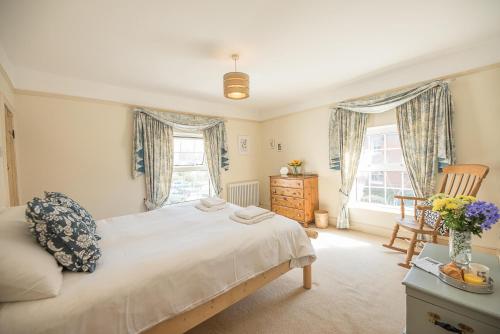 a bedroom with a bed and a chair and windows at Abigail's Cottage Air Manage Suffolk in Woodbridge