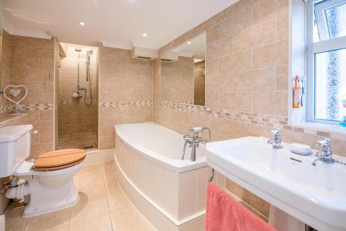 a bathroom with a tub and a toilet and a sink at Abigail's Cottage, Wickham Market in Woodbridge