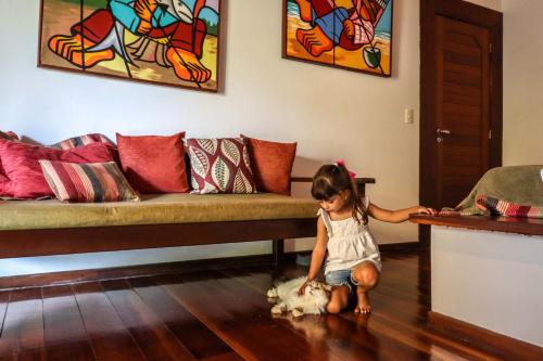a little girl playing with a dog in a living room at Domus Villas in Pipa