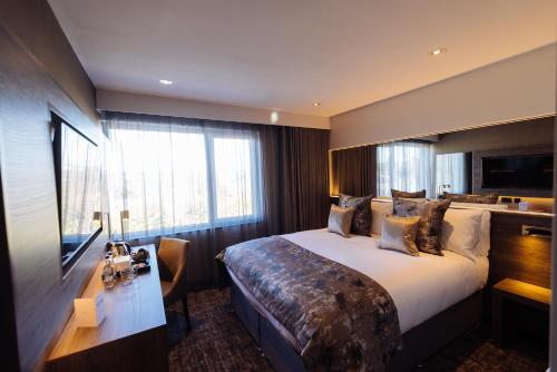 ギフノックにあるThe Redhurst Hotel Glasgowの大きなベッドとデスクが備わるホテルルームです。