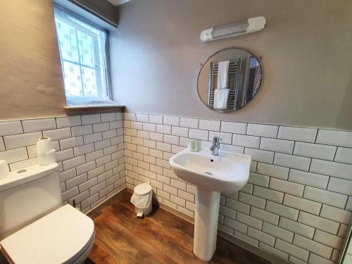 a bathroom with a sink and a toilet and a mirror at Holmwood House Guest Accommodation in York