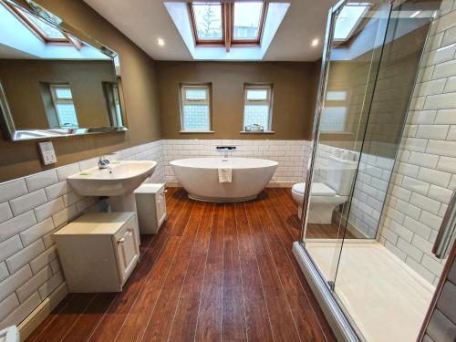 a bathroom with a tub and a sink and a shower at Holmwood House Guest Accommodation in York