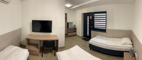 a room with two beds and a desk and a television at Ludowa Restauracja & Noclegi in Kietrz