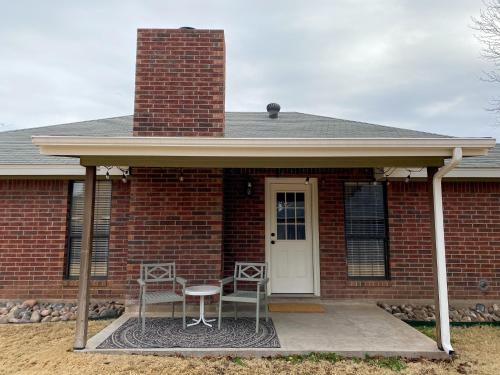 a brick house with two chairs and a table at The Pearl: A Fully Updated 3 Bedroom Home Near ACU in Abilene