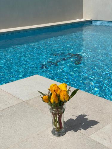 a vase filled with yellow flowers next to a swimming pool at Hostal Puerto Genovés in San José