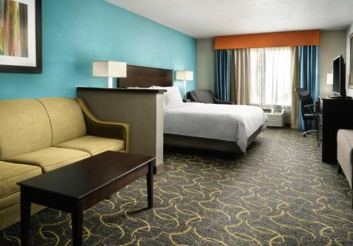 a hotel room with a bed and a couch at Holiday Inn Express Hotel and Suites DFW-Grapevine by IHG in Grapevine