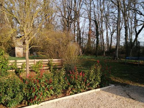 a wooden bench in a park with flowers and trees at Gîte vacances Bosc d'esquirol 4 pers in Escorneboeuf