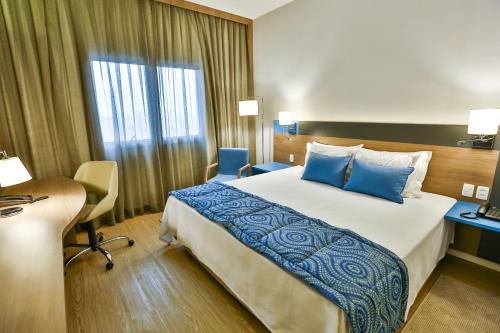 a hotel room with a large bed and a desk at Hilton Garden Inn Santo Andre in Santo André