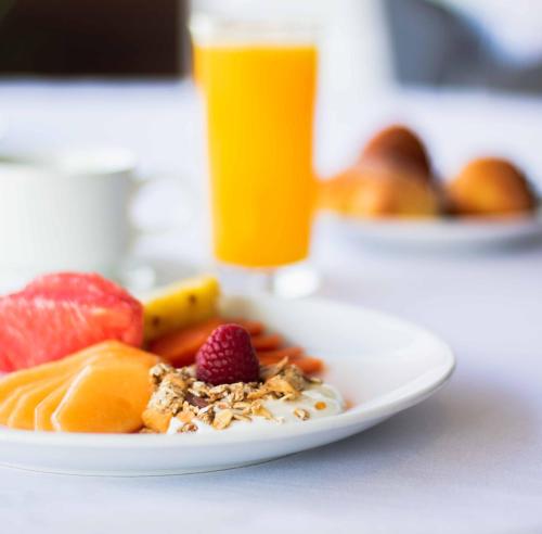 a plate of fruit on a table with a glass of orange juice at Domun Hotel in Querétaro