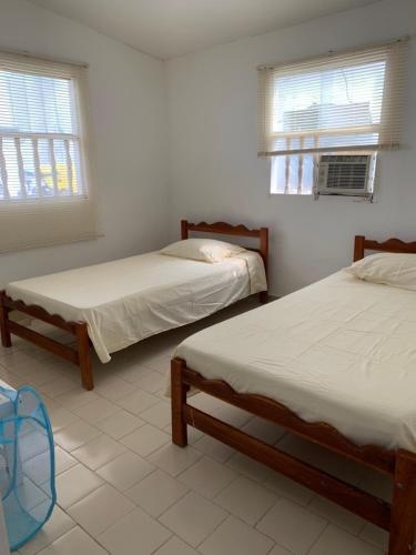 two beds in a room with two windows at "Casa Viña Del Mar" Playa Blanca in San Antero