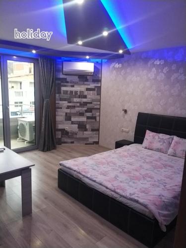 a bedroom with a bed in a room with blue lights at "При братята" - Apartments & Studios in Sandanski