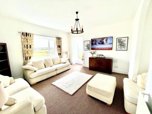 a living room with white furniture and a window at Clydfan in Holyhead