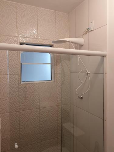 a shower with a glass door and a window at Aconchego do Vale in Blumenau