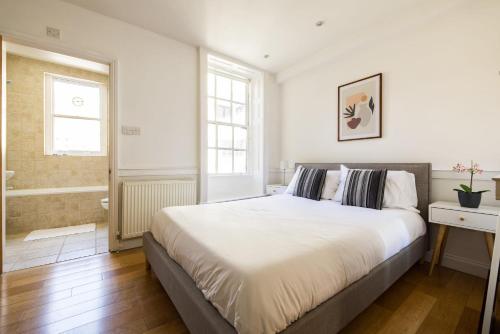 a white bedroom with a large bed and a bathroom at Contemporary 1 Bedroom Bloomsbury Apartment in London