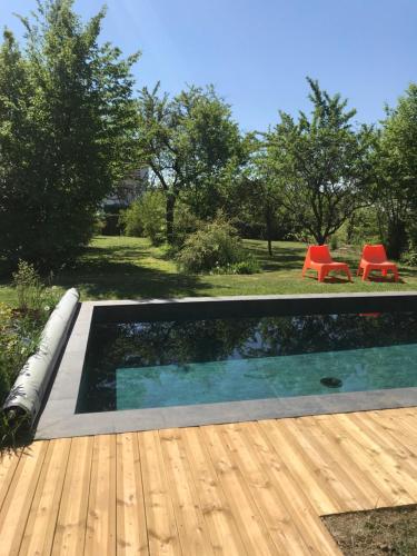 a swimming pool in a yard with a wooden deck at Côté Verger in Vittel