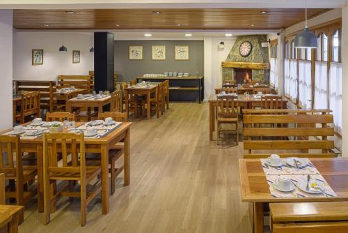 un restaurante con mesas y sillas de madera y chimenea en Hotel Intermonti en San Martín de los Andes