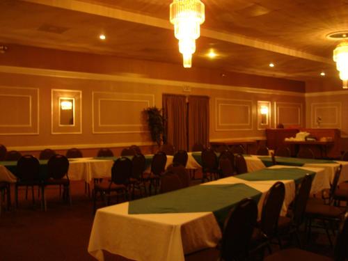 um salão de banquetes com mesas, cadeiras e lustres em Blue Bird Hotel em Melfort