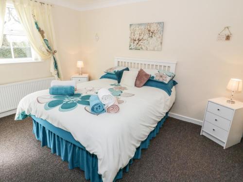 a bedroom with a large white bed with blue pillows at Bodegri Cottage in Llanfflewyn