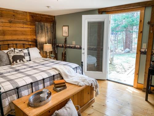 a bedroom with a bed and a table and a door at Inn on Golden Pond in Holderness