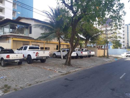 a row of white trucks parked on the side of a street at Pousada Portal do Cabo in João Pessoa