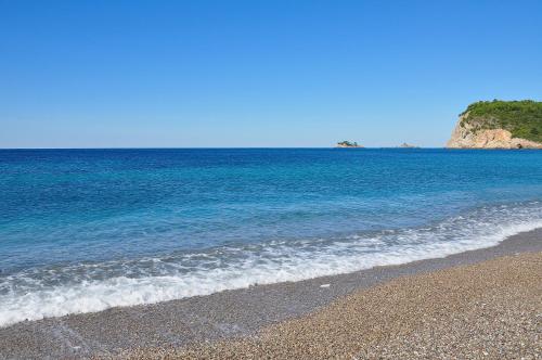 a beach with blue water and a rocky shore at Apartments Villa Marija in Petrovac na Moru