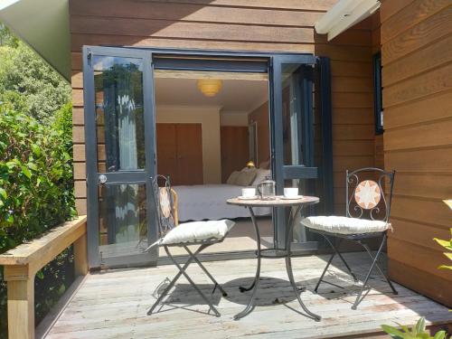a patio with two chairs and a table and a bed at Dangela Boutique Lodge in Auckland