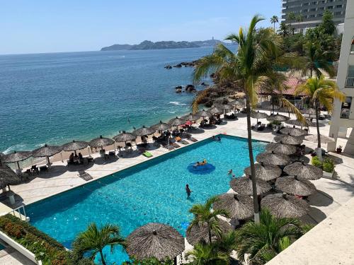 una vista aérea de una piscina con sombrillas y el océano en Suite frente al mar en el corazón de Acapulco en Acapulco