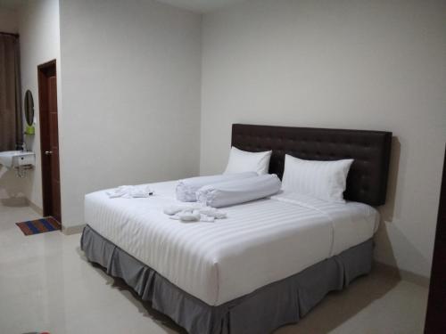 uma cama com lençóis brancos e toalhas brancas em Victory Hotel em Ruteng