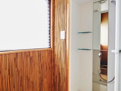 a bathroom with a wooden door and a window at Hostel & Tatami Bar Uchikobare -内子晴れ- in Uchiko