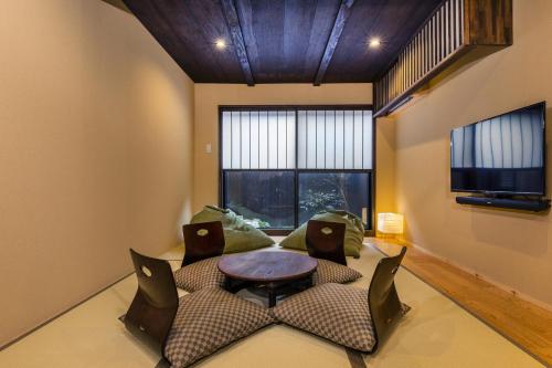 a living room with a table and chairs and a tv at Shiki Homes KUMEI in Kyoto