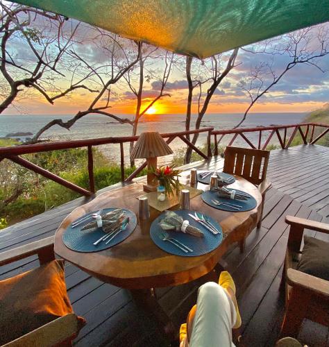 a table on a deck with a view of the ocean at TreeTops Inn in San Juanillo