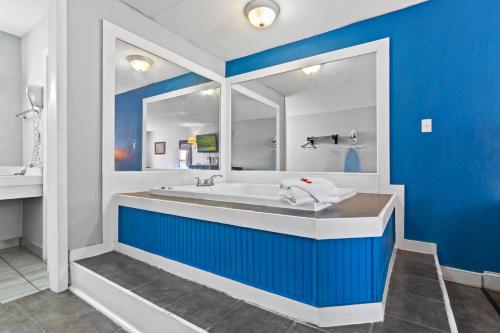 a blue bathroom with a tub and a mirror at Econo Lodge Inn & Suites Virginia Beach - Norfolk in Virginia Beach