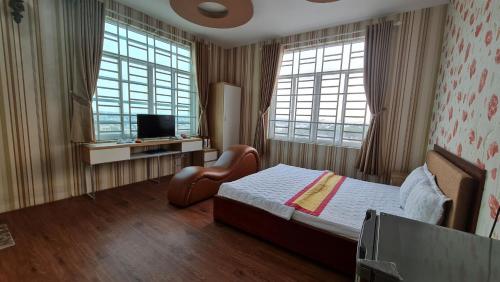 a bedroom with a bed and a tv and two windows at Sky Hotel in Bien Hoa