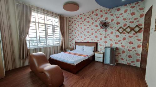 a bedroom with a bed and a chair in it at Sky Hotel in Bien Hoa