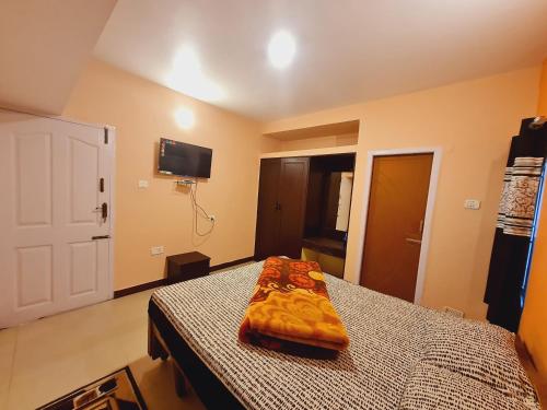 a bedroom with a bed and a tv on the wall at IMPERIAL COTTAGE, HILL BUNK OOTY in Ooty