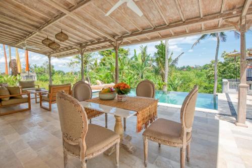 a dining room with a table and chairs and a pool at Wake in Paradise and Luxury Lebah Villas in Ubud