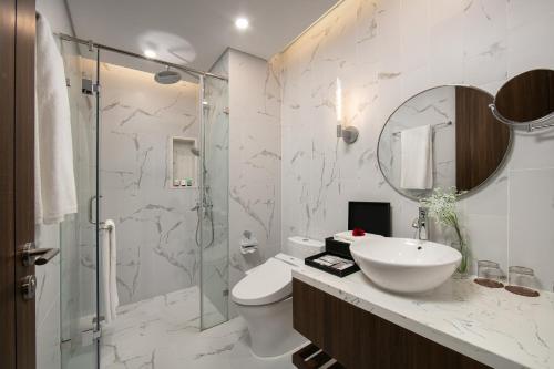 a bathroom with a toilet and a sink and a shower at Mövenpick Living West Hanoi in Hanoi