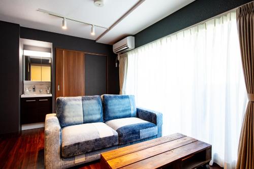 a living room with a blue couch and a table at VILLA KOSHIDO KOTONI annex in Sapporo