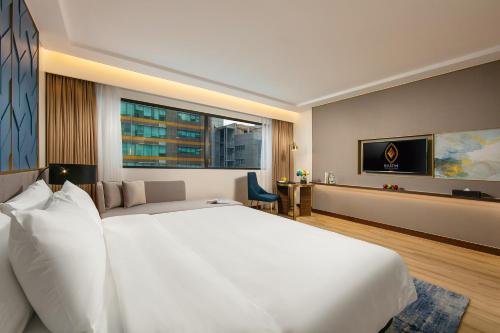 a bedroom with a large white bed and a large window at Mövenpick Living West Hanoi in Hanoi