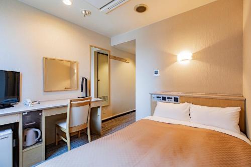 金沢市にある金沢セントラルホテル 本館のベッド、デスク、テレビが備わるホテルルームです。